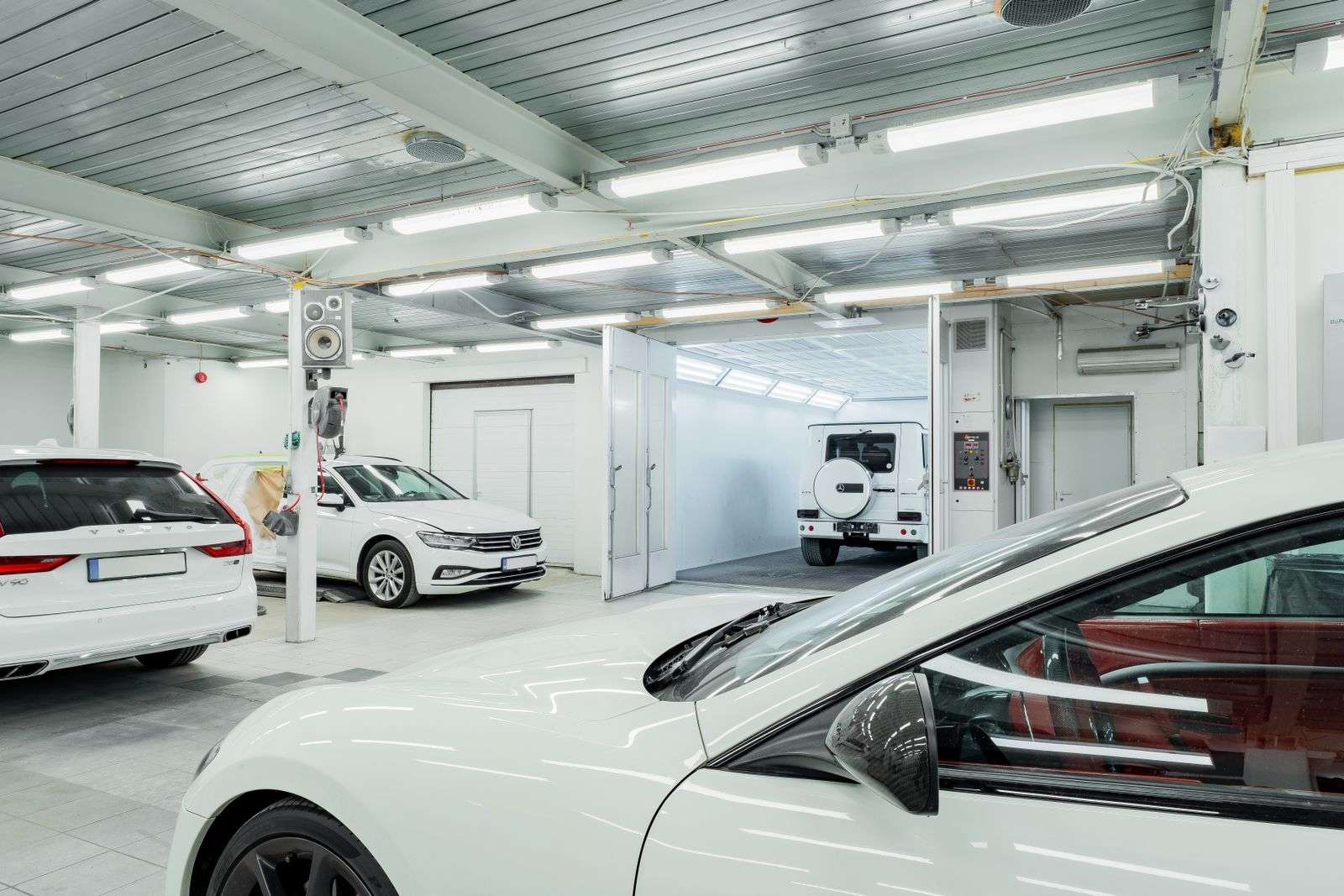 Interior amplo de oficina automotiva com cabine de pintura ao fundo